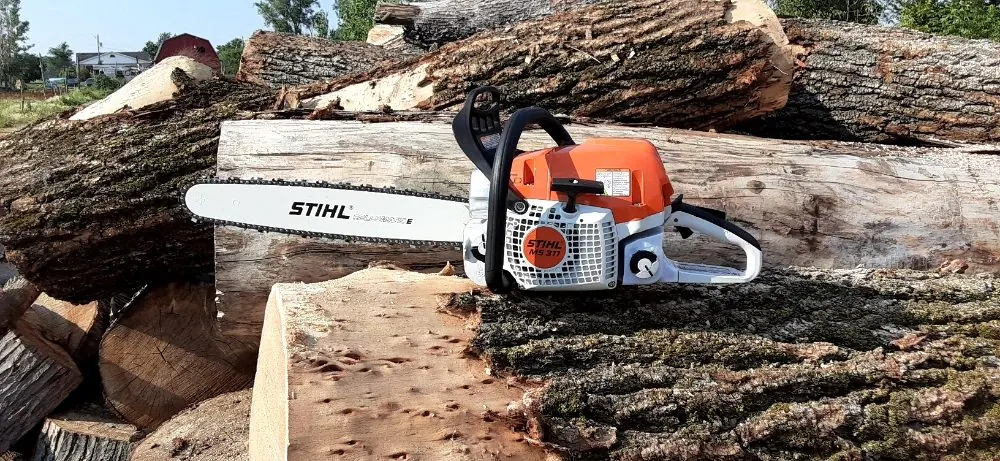 Stihl chainsaw resting on a stack of cut logs